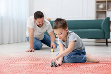 Baba ve oğul evde sıcak zeminde oynuyorlar. Yeraltı ısıtma sistemiyle çifte maruz kalıyorlar.