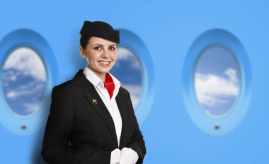 Hostes uçaktaki pencerelerin yanında gülümsüyor.