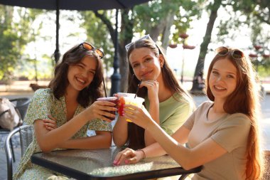 Arkadaşlar açık kafede içeceklerin tadını çıkarıyorlar.