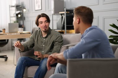 Ofisteki koltuklarda sohbet eden meslektaşlar.