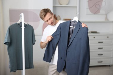 Hazırlanıyor. Genç adam evde kıyafet seçiyor.