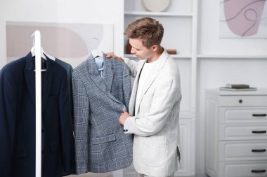 Hazırlanıyor. Genç adam evde kıyafet seçiyor.