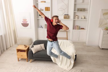 Evde müzik dinlerken zıplayan mutlu bir adam.