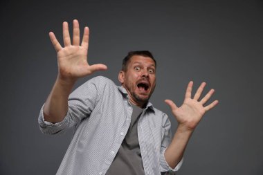 Gri arka planda panik atak geçiren bir adam.