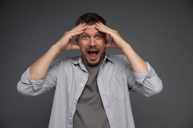 Gri arka planda panik atak geçiren bir adam.