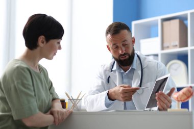 Gastroenterolog klinikteki masada yatan hastaya danışmanlık yapıyor.