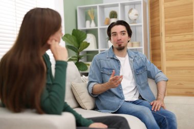 Kadın ve erkek evdeki kanepede konuşuyor.