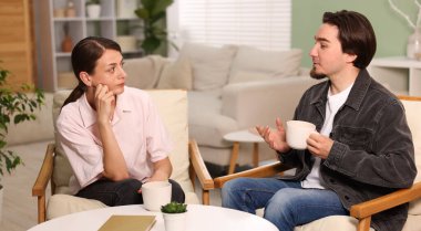 Kadın ve erkek evde çay içerken konuşuyor.