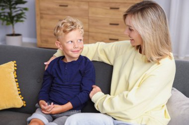 Mutlu anne ve oğlu evdeki kanepede. Aile