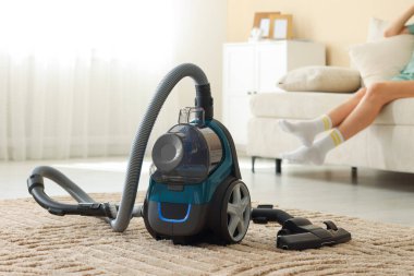 Evdeki kanepede dinlenen kadın, elektrik süpürgesine odaklan.