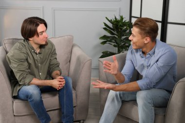 Ofisteki koltuklarda sohbet eden meslektaşlar.