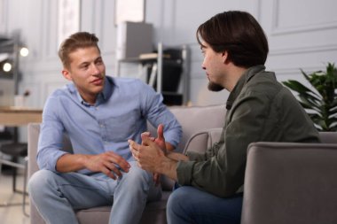 Ofisteki koltuklarda sohbet eden meslektaşlar.