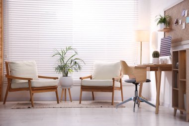 Ev ofisinde ahşap masası, bilgisayarı ve koltukları olan şık bir iş yeri. İç tasarım