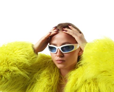 Beyaz arka planda poz veren şık güneş gözlüklü ve kürklü güzel bir kadın.