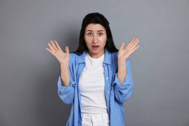 Gri arka planda panik atak geçiren kadın.