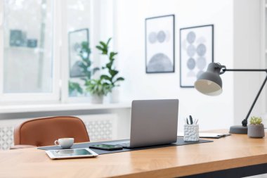 Modern dizüstü bilgisayarı ve ahşap masa üzerindeki kırtasiyesi olan şık bir iş yeri.