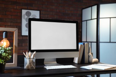 Bilgisayar, ev bitkisi, lamba ve kırtasiye malzemesi.