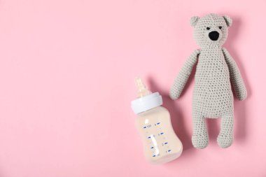 Pembe arka planda mama şişesi ve oyuncak ayıyla besleniyor. Metin için boşluk