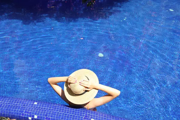 Güneşli bir günde, açık havada havuzda hasır şapkalı bir kız.