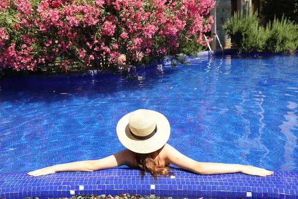Güneşli bir günde yüzme havuzunda hasır şapkalı bir kız.