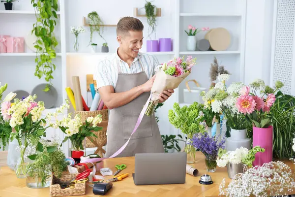 Profesyonel çiçekçi dükkandaki ahşap masada çiçek buketi yapıyor.