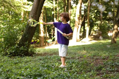 Küçük şirin çocuk parkta sabun köpüğüyle eğleniyor.
