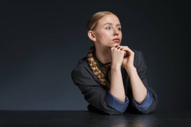 Takım elbiseli güzel bir kadın karanlık arka planda masada poz veriyor. Metin için boşluk