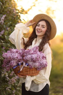 Gülen bir kadın ve açık havada bir sepet leylak çiçeği.