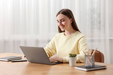 İçerideki ahşap masada dizüstü bilgisayar kullanan metin yazarı