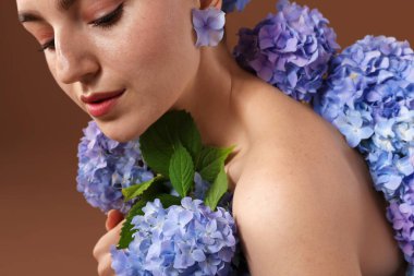 Kahverengi arka planda Hortensiya çiçekleri olan güzel bir genç kadın, yakın plan.