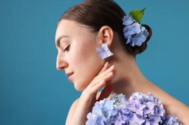 Mavi arka planda hortensiya çiçekleri olan güzel genç bir kadın.