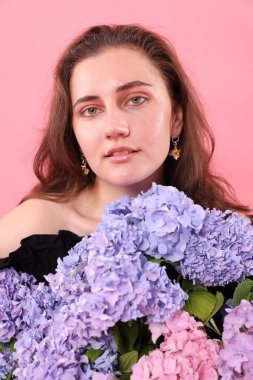Pembe arka planda Hortensiya çiçekleri olan güzel bir kadının portresi