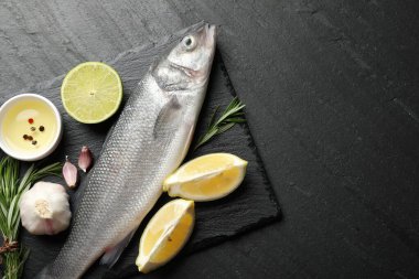 Siyah masadaki baharatlı taze çiğ deniz kabuğu balığı, üst görünüm ve metin için yer. Deniz ürünleri lezzetleri.