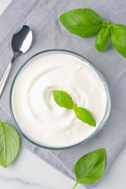 Lezzetli yoğurt ve fesleğen beyaz masada, düz yerde.