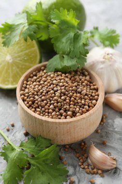 Kişniş tohumu, taze kişniş, kireç ve sarımsak gri desenli masa, yakın plan.