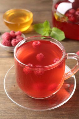 Aromatik ahududu çayı, böğürtlen, nane ve bal ahşap masada, yakın plan.