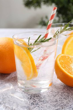 Portakal dilimli soda ve gri masada biberiye, yakın plan.