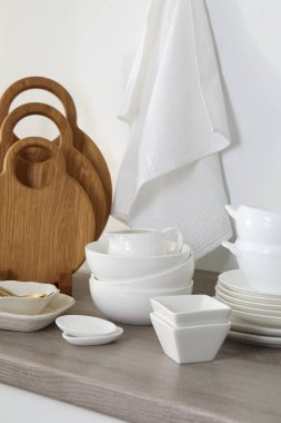 Mutfakta farklı beyaz bulaşık takımları ve tahta kesme tahtaları var.