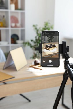 Stüdyoda akıllı telefonlu çikolatalı kek çekmek, seçici odaklanma. Profesyonel yemek fotoğrafçılığı.