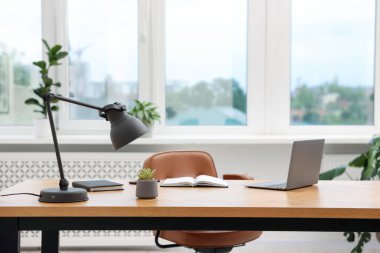 Modern dizüstü bilgisayarı ve ahşap masa üzerindeki kırtasiyesi olan şık bir iş yeri.