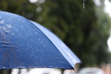Dışarıda sağanak yağmur altında mavi şemsiye, yakın çekim. Metin için boşluk