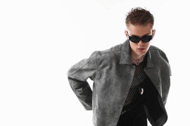 Beyaz arka planda şık ceket ve güneş gözlüğü takan yakışıklı bir genç.