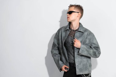 Beyaz arka planda ceket ve güneş gözlüğü takan yakışıklı genç adam, mesaj için yer var.