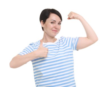 Kuvvet. Güzel bir kadın beyaz arka planda bisepslerini ve başparmaklarını gösteriyor.