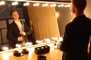 Kravatlı adam içeride aynanın yanında hazırlanıyor.