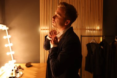 Şık giyinmiş bir adam içeride hazırlanıyor.