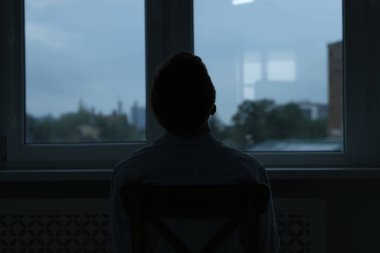 Üzüntü ve depresyon. Evin penceresinin yanındaki siluet, arka plan.