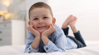 Evde yatakta gülümseyen küçük çocuk
