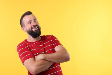 Sarı arka planda kollarını kavuşturup gülen yakışıklı bir adam. Metin için boşluk