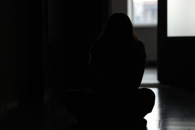 Evdeki üzgün genç kadının silueti.